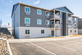 a blue and white apartment building with a parking lot at Altitude, East Wenatchee